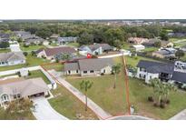 Charming single-story home featuring a well-manicured front lawn with mature palm trees and a classic driveway at 1855 Cavalier Ct, Kissimmee, FL 34744