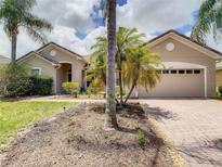 Tan one-story house with a two-car garage and lush landscaping at 3634 Northwoods Dr, Kissimmee, FL 34746