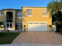 Inviting two-story home with a well-maintained lawn, attached two car garage, and tasteful landscaping at 2606 Royal Fern Pl, Kissimmee, FL 34758