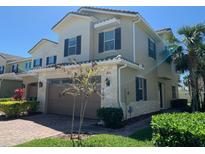 Two-story home featuring a brick driveway, two-car garage, and a well-maintained front lawn with tropical landscaping at 9793 Winnington St, Orlando, FL 32832