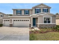 Charming two-story home features a two-car garage, teal shutters and door, and stone accents at 1488 August Gray Dr, Kissimmee, FL 34744