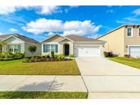 Charming single-story home with a well-manicured lawn, driveway, and attached two-car garage at 527 Noble Ave, Davenport, FL 33837