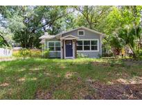Charming single-story home with a blue front door and lush landscaping surrounding the property at 527 Noble Ave, Davenport, FL 33837