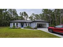 Newly built home with a gray exterior, two-car garage, and landscaped front yard at 6817 Sw 131St Pl, Ocala, FL 34473