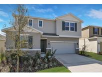 Two-story home featuring a two-car garage, neutral siding, and a well-manicured lawn at 5414 Catmint Dr, Lake Hamilton, FL 33851