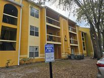 View of a yellow two-story apartment complex building with balconies and a handicapped parking sign at 5267 Images Cir # 303, Kissimmee, FL 34746