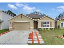 Tan house with brown shutters, landscaped yard, and a paved driveway at 965 Shady Tree Ln, Davenport, FL 33897