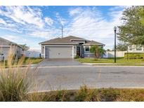 Single-story home with gray exterior, paver driveway, and landscaped lawn at 113 Promenade Ct, Auburndale, FL 33823