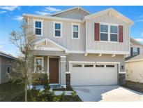 Charming two-story home featuring a two-car garage, landscaped yard, and light gray siding at 211 Bull Frog Ln, Umatilla, FL 32784