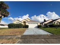 Cute yellow house with a two-car garage and well-manicured lawn at 2511 La Jolla Trl, Kissimmee, FL 34747