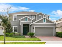 Two story house with gray siding, teal front door, and two car garage at 1317 Yorkdale Rd, Davenport, FL 33837