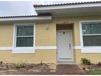 House exterior featuring a light yellow painted stucco, a white door, and a brick walkway at 1645 Cumin Dr, Kissimmee, FL 34759