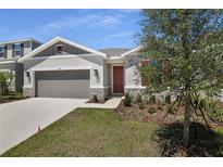 Charming home featuring a manicured lawn, stone accents, and a two-car garage at 1695 Sugarbelle Cir, Mascotte, FL 34753