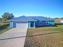 Single-story home with metal roof, attached garage, and grassy yard at 25 Juniper Loop Cir, Ocala, FL 34480