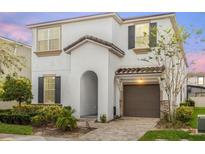Two-story house with brown garage door and landscaping at 9022 Pelican Cove Trce, Kissimmee, FL 34747