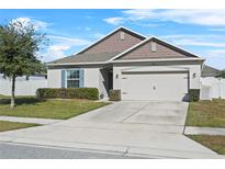 One-story home with neutral siding, two-car garage, and landscaped lawn at 15335 White Tail Loop, Mascotte, FL 34753