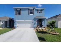 Charming two-story home with landscaped yard, blue exterior, and attached two-car garage at 2459 Taloncrest Ct, Eagle Lake, FL 33839