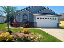 Charming exterior of a well-maintained single Gathering home with a lush lawn and landscaped flower beds at 2645 Oneida Loop, Kissimmee, FL 34747