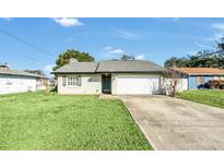 Charming single story home with a well-manicured lawn and attached garage at 1607 W Oak St, Kissimmee, FL 34741