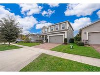Two-story house with gray siding, brick driveway, and landscaped lawn at 437 Seattle Slew Dr, Davenport, FL 33837