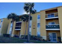 Two-story condo building with palm trees and landscaping at 5275 Images Cir # 204, Kissimmee, FL 34746