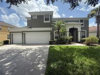 Beautiful two-story home featuring a three car garage, lush lawn, and tropical landscaping at 8557 La Isla Dr, Kissimmee, FL 34747