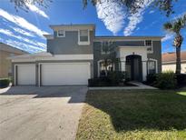 Two-story house with a three-car garage and lush lawn at 8557 La Isla Dr, Kissimmee, FL 34747