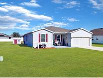 Gray house with red shutters, landscaping, and detached shed at 905 Desmoines Way, Poinciana, FL 34759