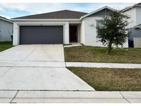 Single-story house with gray garage door and a well-maintained lawn at 1655 Aspen Ave, Davenport, FL 33837