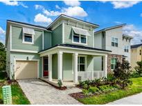 Two-story craftsman style home with green siding, white columns, and a paved driveway at 1829 Tropical Palms Cir Cir, Kissimmee, FL 34747