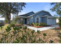 One-story house with blue exterior, landscaped yard, and attached garage at 201 Steamboat Blvd, Davenport, FL 33897