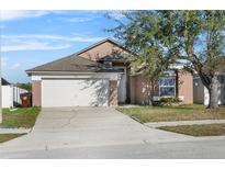 Tan house with white garage door and landscaping at 2415 Black Powder Ln, Kissimmee, FL 34743