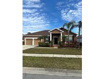 Tan one-story house with two-car garage, palm trees, and well-maintained lawn at 3061 Palermo Rose Way, Kissimmee, FL 34746