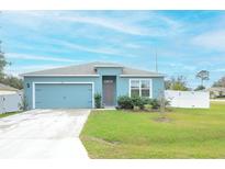 One-story house with blue exterior, two-car garage, and landscaped yard at 233 Tiffany Ct, Kissimmee, FL 34758