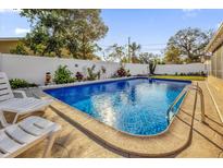Backyard in-ground pool with landscaping, a white fence, and lounge chairs at 306 Boger N Blvd, Lakeland, FL 33803
