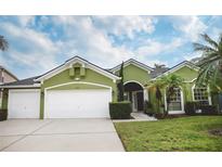 Green house exterior with two-car garage and landscaped lawn at 3201 Hanging Moss Cir, Kissimmee, FL 34741