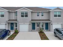 Three-unit townhome building with gray exterior, two-car garages, and landscaping at 4078 Malawi Trl, Saint Cloud, FL 34772