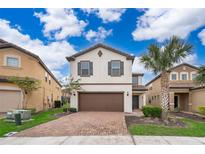 Two-story house with brown garage door and brick driveway, surrounded by palm trees at 5505 Misty Oak Cir, Davenport, FL 33837