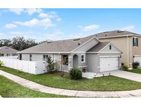 Gray house with white fence and landscaping at 1956 Egret Meadows Ave, Kissimmee, FL 34744