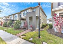 Two-story townhome with modern facade, landscaped front yard, and brick pathway at 2274 Centerra Loop, Kissimmee, FL 34741