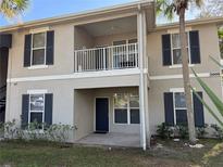 Two-story condo building with light beige exterior, dark gray shutters, and a private balcony at 3011 Hemingway Cir # 3011, Haines City, FL 33844