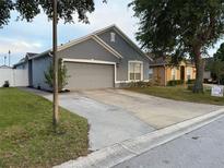 Charming single-Gathering home featuring a gray exterior, two-car garage, and well-maintained landscaping at 435 Madina Cir, Davenport, FL 33837