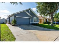 Charming blue home featuring an attached garage and well-manicured lawn at 435 Madina Cir, Davenport, FL 33837