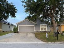Charming single-story home featuring a gray exterior, a two-car garage, and a well-maintained front yard at 435 Madina Cir, Davenport, FL 33837