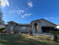 Brick house with a two-car garage and solar panels at 648 Tradewinds Dr, Deltona, FL 32738