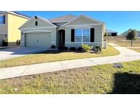 One-story house with green exterior, two-car garage, and landscaped yard at 120 Panda Way, Davenport, FL 33837