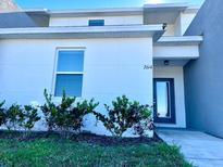 Modern two-story home with gray and white exterior, landscaping, and a front door at 2614 Old Kent Cir, Kissimmee, FL 34758