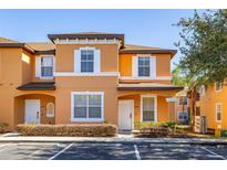 Attractive two-story townhome with orange exterior, white trim, and landscaping at 2713 Roadster Ln, Kissimmee, FL 34746