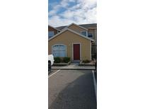 Tan two-story townhome with red door and landscaping at 420 Australian Way, Davenport, FL 33897
