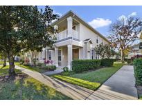 Two-story townhome with light beige exterior, balcony, and landscaping at 7136 Red Lantern Dr # 7136, Harmony, FL 34773
